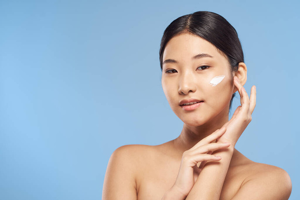 Joven mujer asiática aplicando crema hidratante en su cara
  - Foto, Imagen