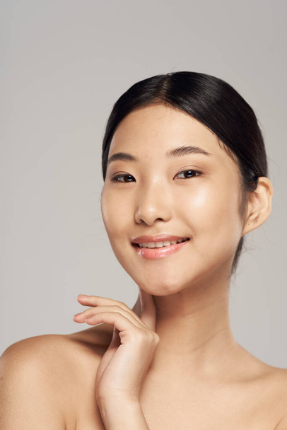 Studio záběr. Mladá asijská žena se usmívá na šedém pozadí - Fotografie, Obrázek