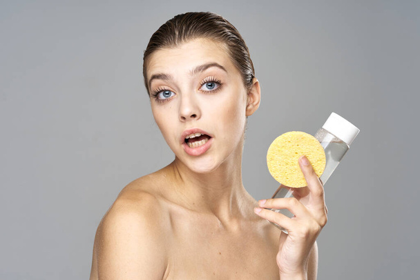 fiatal gyönyörű nő tisztítja a bőrét szivaccsal és micelláris vízzel  - Fotó, kép
