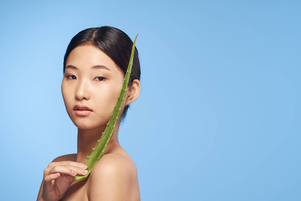 Молодая красивая азиатская женщина позирует с листком алоэ вера  - Фото, изображение