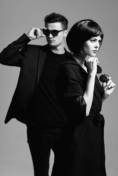 Jeune beau couple en lunettes de soleil posant en studio. Noir et blanc.    - Photo, image