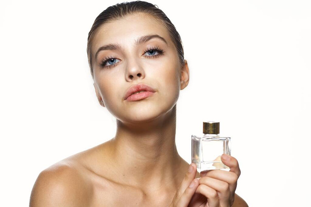 Egy fiatal, gyönyörű nő arcképe parfümös üveggel. Stúdió felvétel.   - Fotó, kép