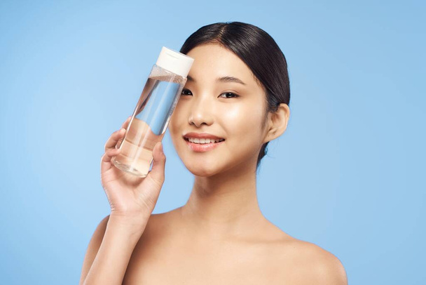 красива азіатська жінка тримає пляшку продукту зі шкіри
 - Фото, зображення