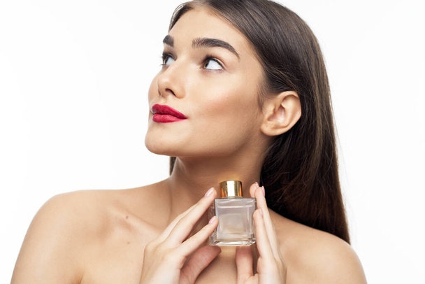 Портрет молодой красивой женщины с парфюмерной бутылкой на белом фоне
 - Фото, изображение