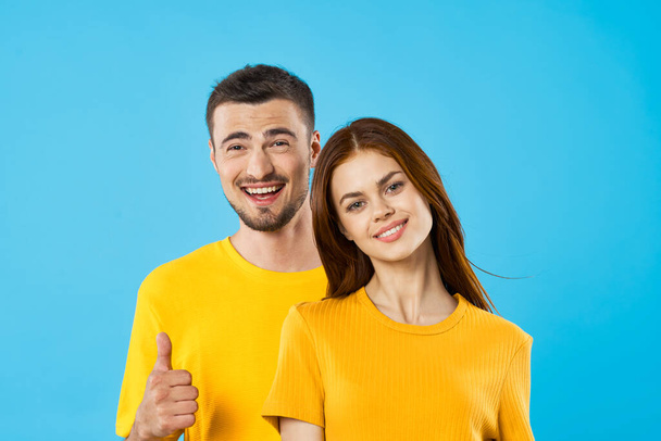 young  handsome man and woman with thumbs up  in studio  on blue background  - Φωτογραφία, εικόνα