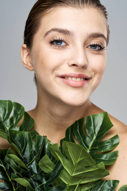 Young beautiful model posing with leaves in studio - Fotoğraf, Görsel