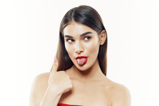Retrato de una joven mujer hermosa mostrando la lengua sobre fondo blanco  - Foto, imagen