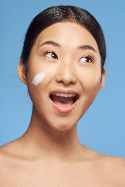 Young asian woman applying moisturizer on her face  - Valokuva, kuva