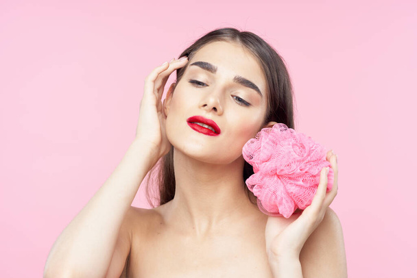 Pielęgnacja skóry i piękno. Portret młodej pięknej kobiety z myjką na różowym tle - Zdjęcie, obraz