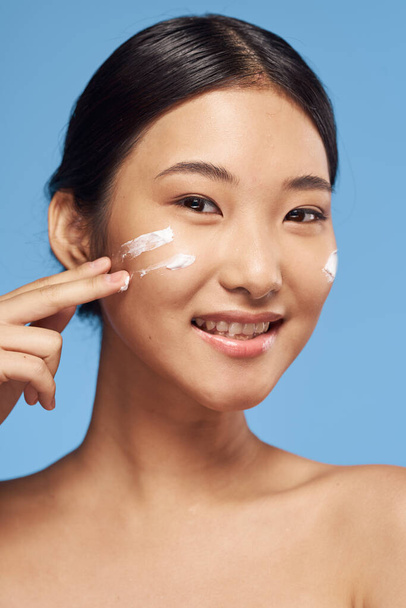 Young asian woman applying moisturizer on her face  - Φωτογραφία, εικόνα