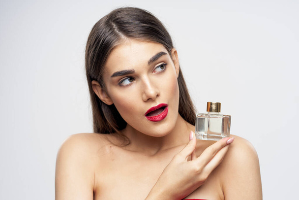 Fiatal gyönyörű nő kezében parfüm üveg a stúdióban - Fotó, kép