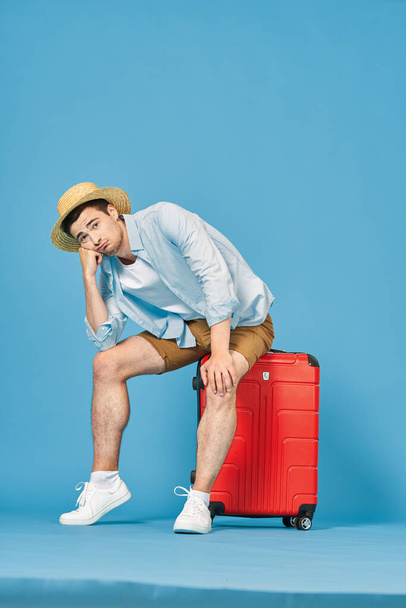 Young man with red suitcase in studio - Фото, изображение
