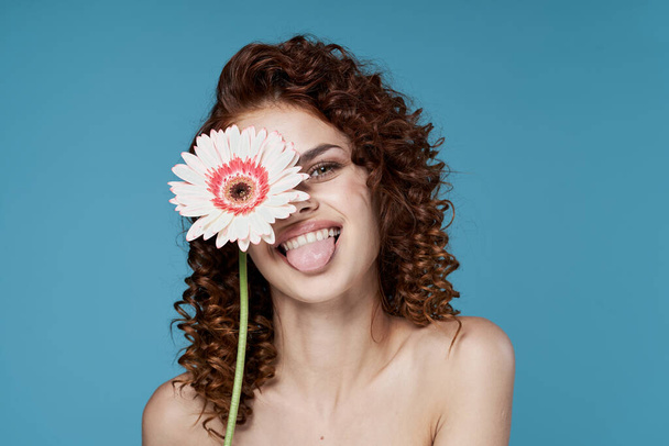 Young woman with flower posing in studio - Фото, изображение