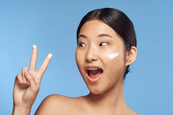 Joven mujer asiática aplicando crema hidratante en su cara
  - Foto, imagen