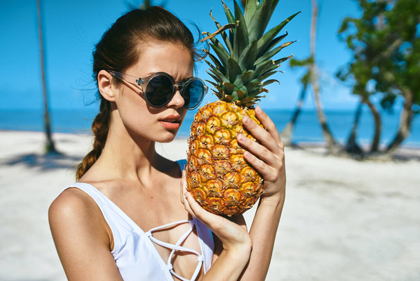 Kobieta w białym stroju kąpielowym z ananasem. Wysokiej jakości zdjęcie - Zdjęcie, obraz