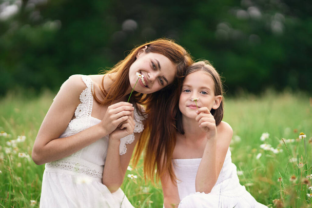 Молодая мать и ее дочь веселятся на ромашковом поле - Фото, изображение