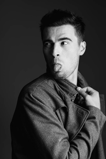 Πορτρέτο του νεαρού όμορφου άνδρα που δείχνει γλώσσα στο στούντιο - Φωτογραφία, εικόνα
