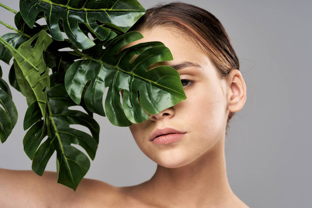 Young beautiful model posing with leaves in studio - Foto, imagen