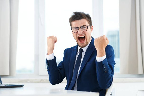 Young  businessman in glasses sitting   in the office celebrating - Foto, Imagem