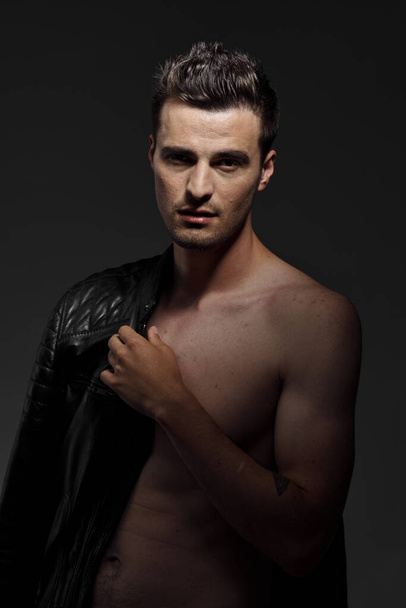 Portrait of young handsome man in black leather jacket posing in studio.  - Foto, immagini