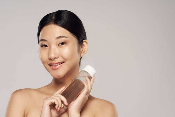 красивая азиатская женщина держит бутылку, косметический продукт
  - Фото, изображение