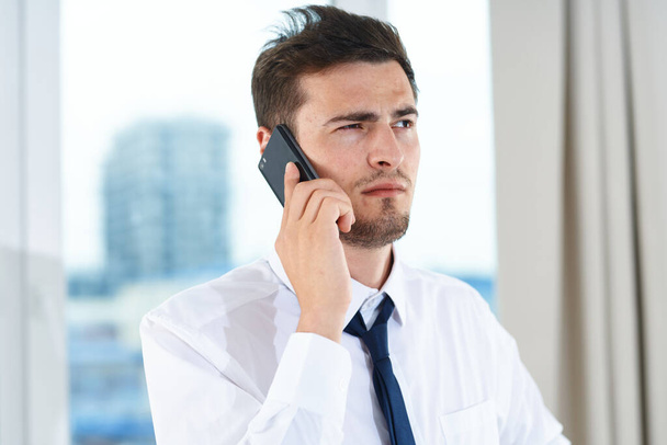 Business concept. Yong  confused businessman talking on smartphone  in the office  - Foto, Imagen