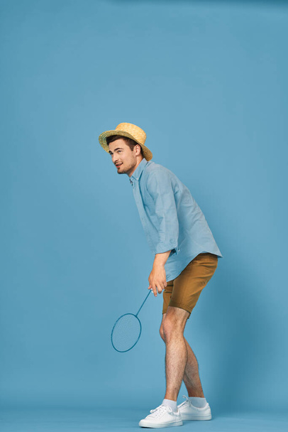 Молодий чоловік грає в теніс ізольовано на синьому фоні, студійний знімок
 - Фото, зображення