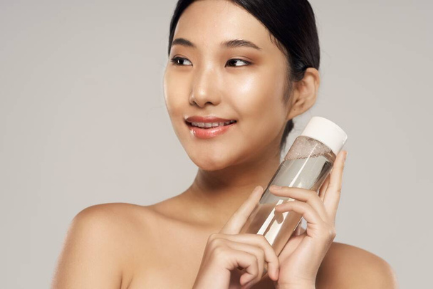 Studio záběr. Portrét mladé asijské ženy s kosmetickým výrobkem - Fotografie, Obrázek