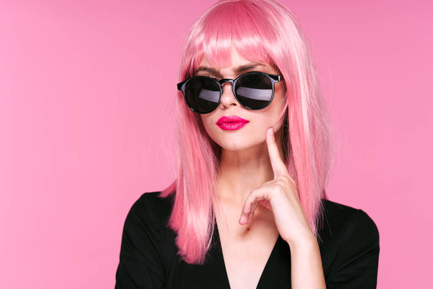 fiatal gyönyörű nő rózsaszín paróka és napszemüveg pózol stúdióban  - Fotó, kép