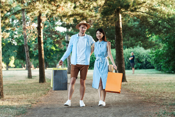νεαρό ζευγάρι με τσάντες ψώνια στο πάρκο - Φωτογραφία, εικόνα