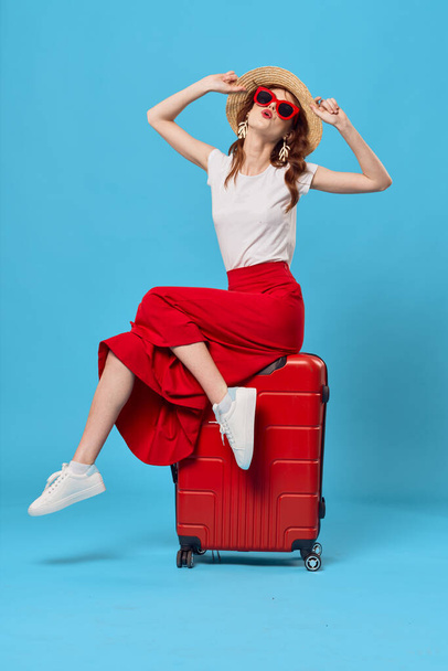Young woman with red suitcase in studio - Фото, зображення