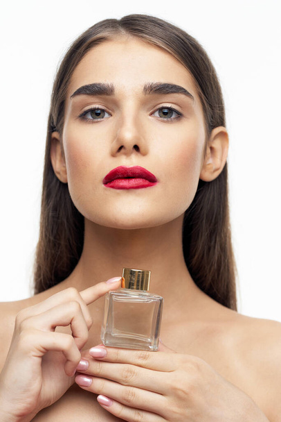 Young beautiful woman holding perfume bottle in studio - Zdjęcie, obraz