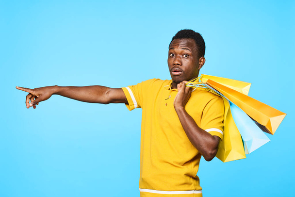 young afrivan man with shopping bagspointing on blue background - Photo, Image