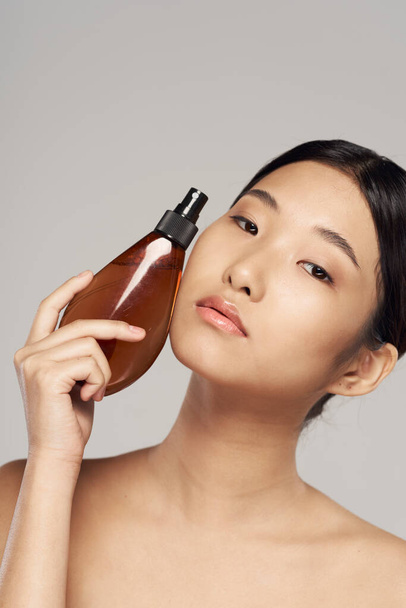 Nuori aasialainen nainen hiuslakkaa studiossa. Kauneus, muoti valokuvaus - Valokuva, kuva