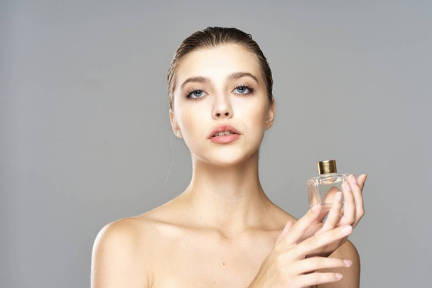 Porträt einer jungen schönen Frau mit Parfümflasche. Studioaufnahme.   - Foto, Bild