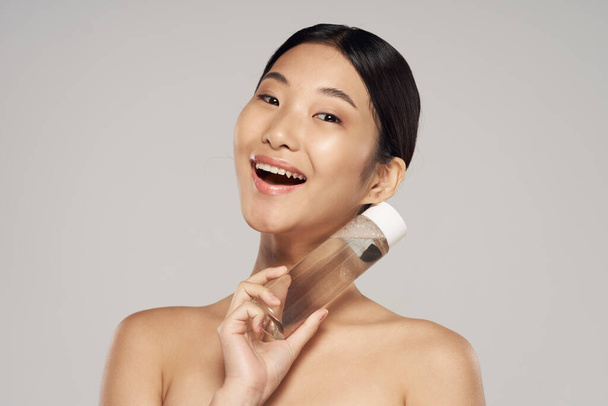 Studio záběr. Portrét mladé asijské ženy s kosmetickým výrobkem - Fotografie, Obrázek