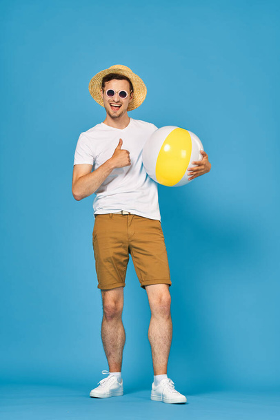 Young man playing with ball in studio showing thumb up - Foto, Imagen