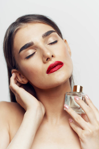 Portret van jonge mooie vrouw met parfum fles geïsoleerd op witte achtergrond - Foto, afbeelding
