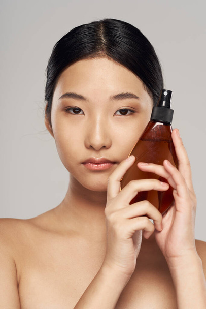 Young asian woman with hair spray in studio. Beauty, fashion photography - Foto, Imagen
