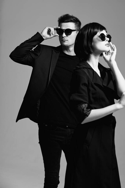 Mladý krásný pár ve slunečních brýlích pózující ve studiu. Černá a bílá.    - Fotografie, Obrázek