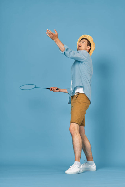 Tenis oynayan genç adam mavi arka planda izole edilmiş, stüdyo çekimi - Fotoğraf, Görsel