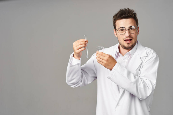 Doctor in glasses showing  test tubes on grey background. Studio shot - Zdjęcie, obraz