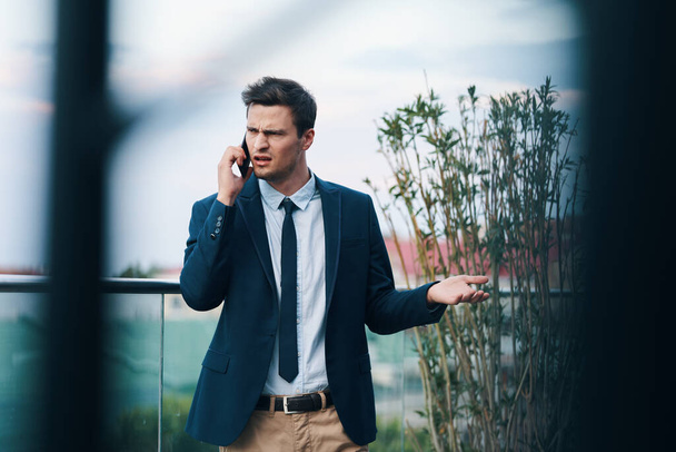 Joven hombre de negocios enojado hablando en smartphone en la calle  - Foto, imagen