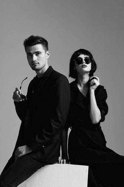 Junges schönes Paar mit Sonnenbrille posiert im Studio. Schwarz-Weiß.    - Foto, Bild
