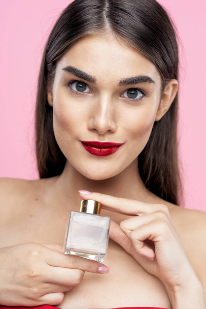 Portrait of young beautiful  woman with perfume bottle. Studio shot - Photo, image