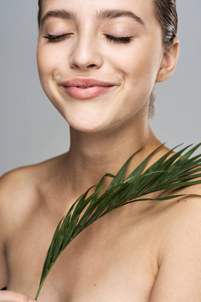 Young beautiful model posing with leaf in studio - Fotografie, Obrázek