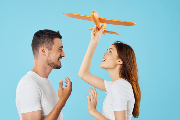 young  couple with toy airplane  in studio, isolated background    - Zdjęcie, obraz