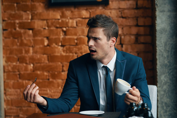 Young  angry businessman   with coffee cup - Photo, Image