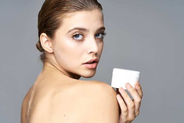 Studio shot of young beautiful woman with cream, beauty product on an isolated background - Foto, afbeelding