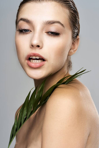Young beautiful model posing with leaf in studio - Foto, Imagen
